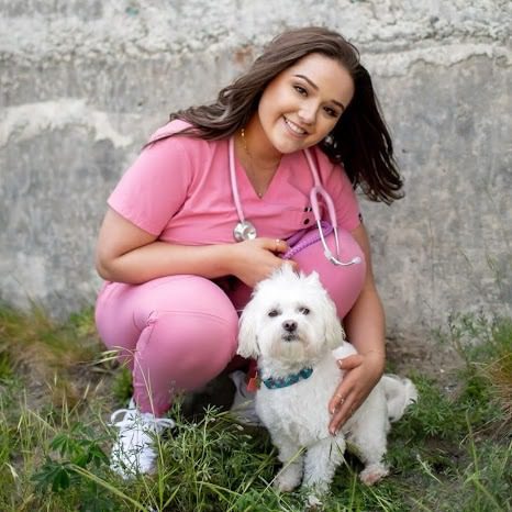 Anette crouching to the ground by her small white dog